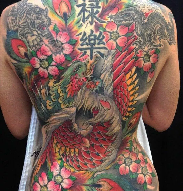 A woman's back showcases a vibrant tattoo featuring a phoenix and intricate floral patterns, resonating with the rich imagery and meanings of Japanese tattoos.