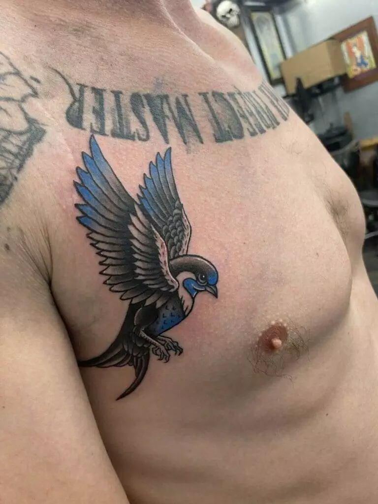 A man with a blue swallow tattoo on his chest.