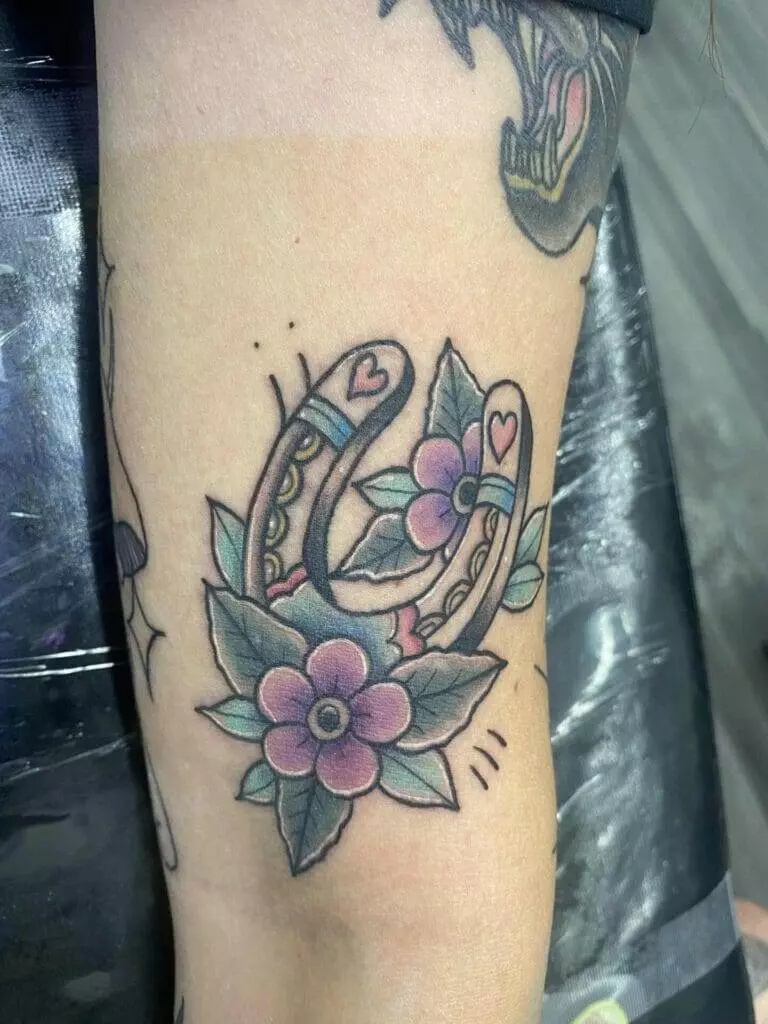 A tattoo of a horseshoe with flowers on it.