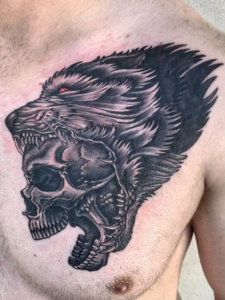 A tattoo of a wolf with a skull on his chest.