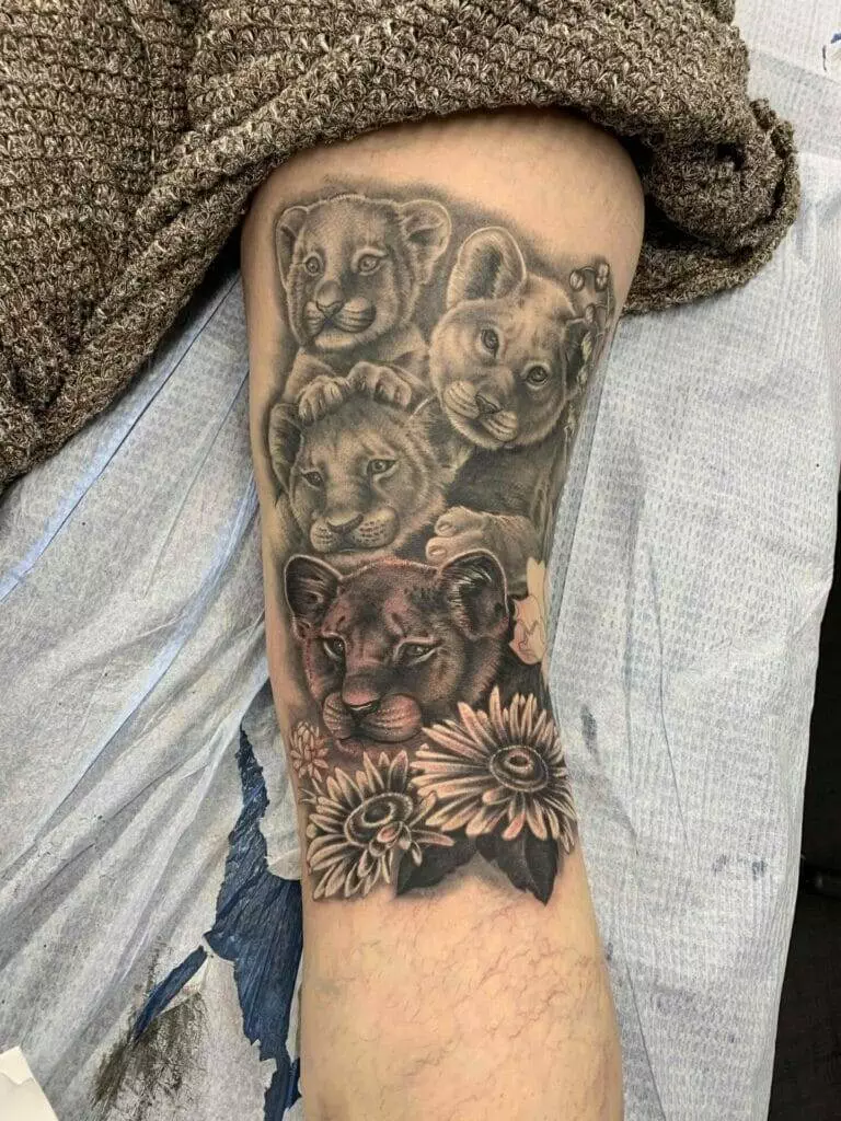 A tattoo of lion cubs and flowers on a person's forearm.