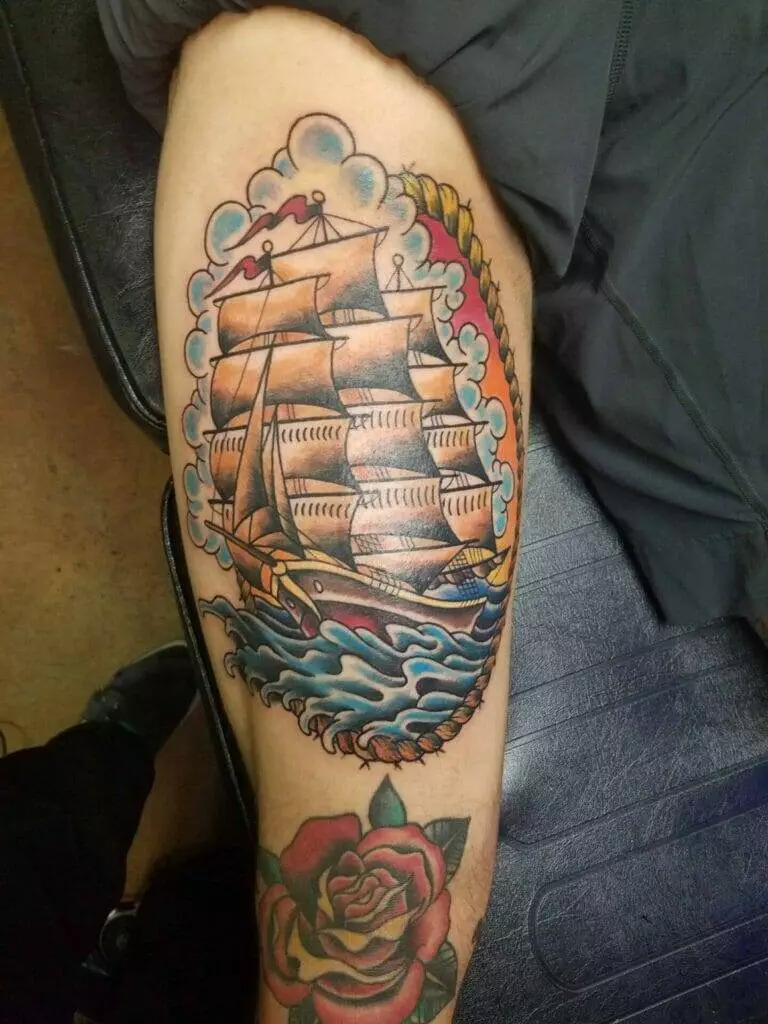 A tattoo of a sailing ship on a man's thigh.