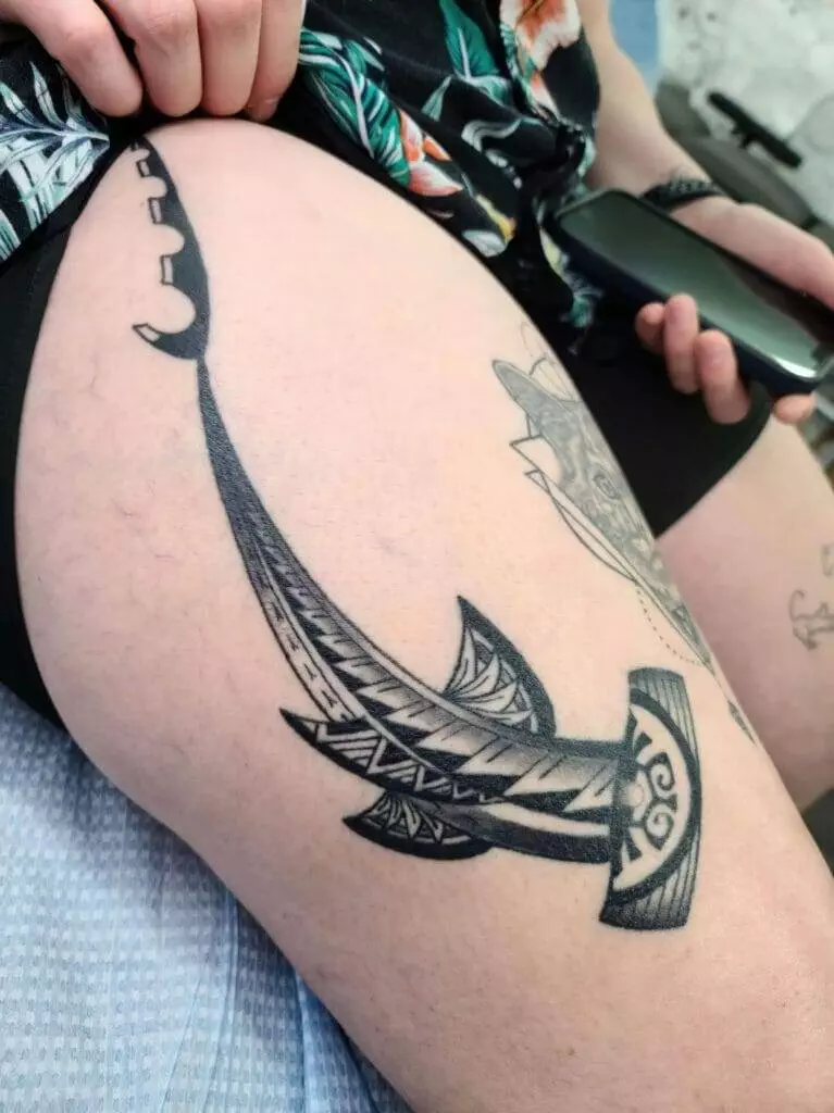 A woman with a tattoo of an anchor on her thigh.