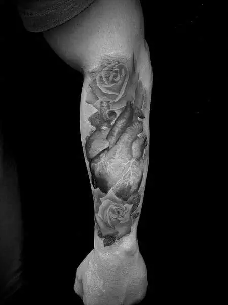 A black and white tattoo of a heart and roses.