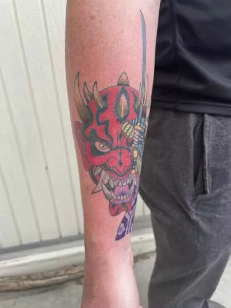 A man's forearm with a tattoo of a samurai.