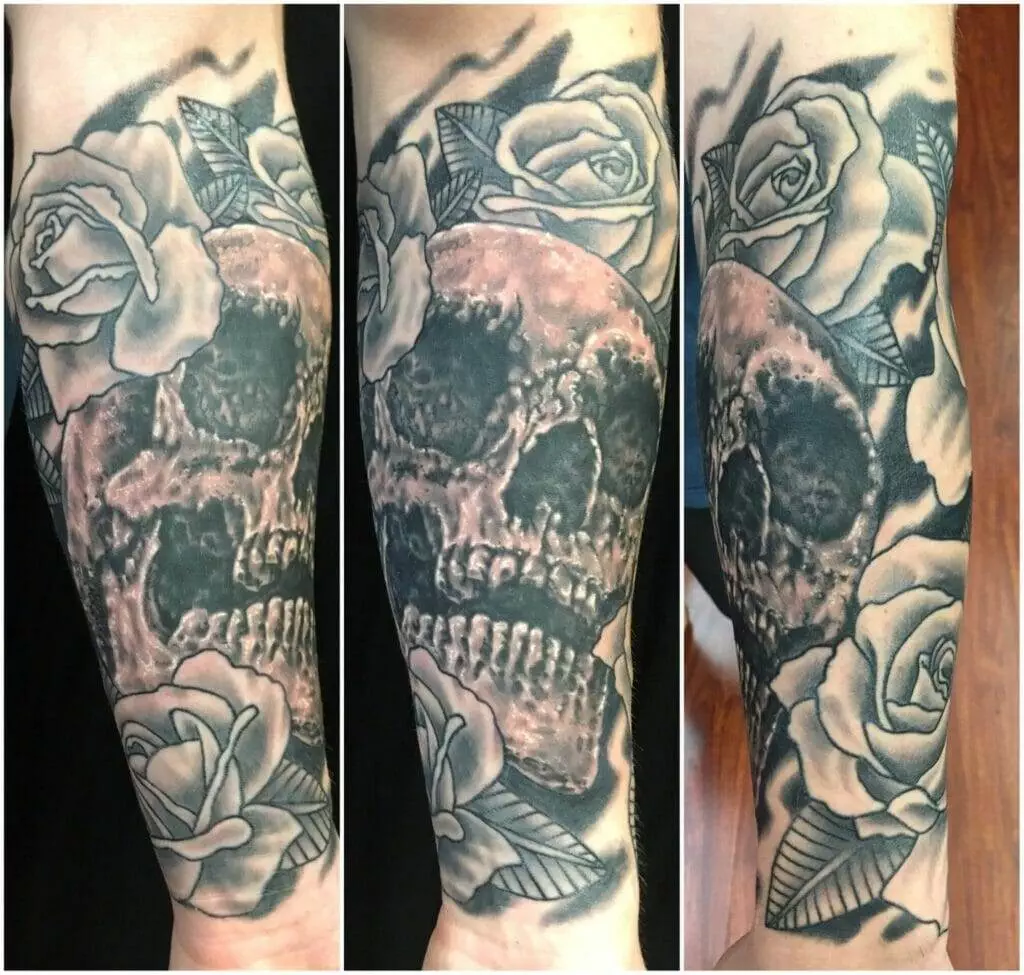 A sleeve tattoo featuring a skull surrounded by roses.