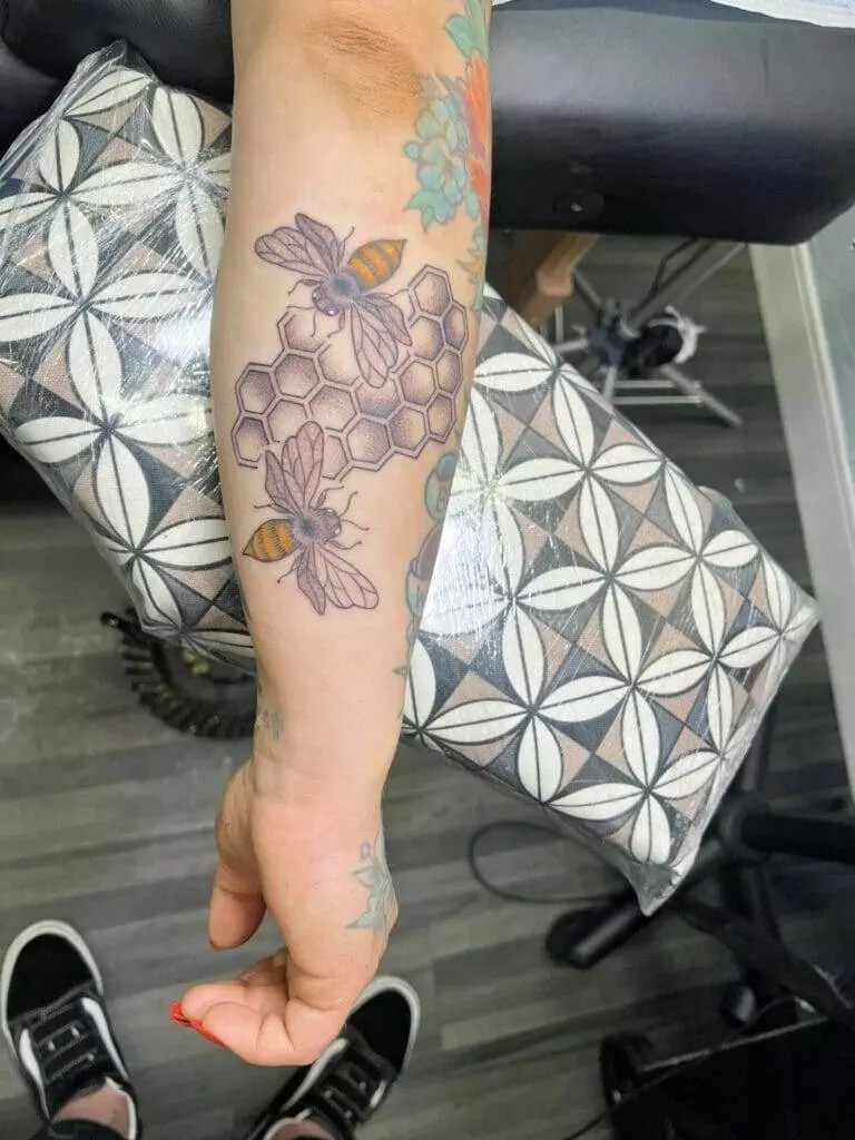 A woman's arm with a bee tattoo on it.