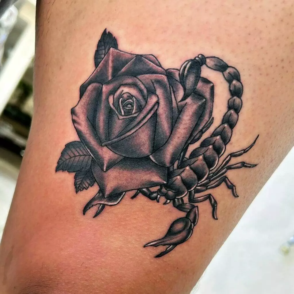 A tattoo of a scorpion and rose on the thigh.