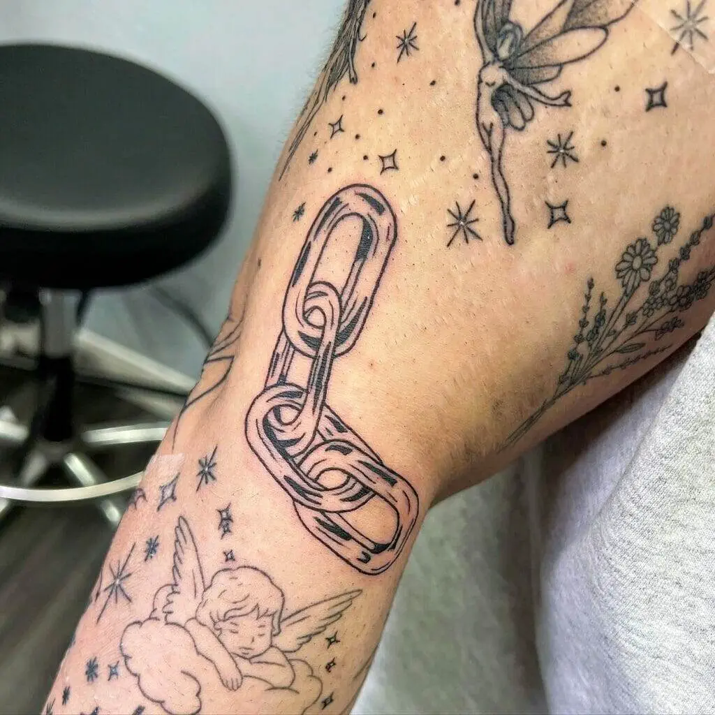 A man's arm with a tattoo of a chain and angels.