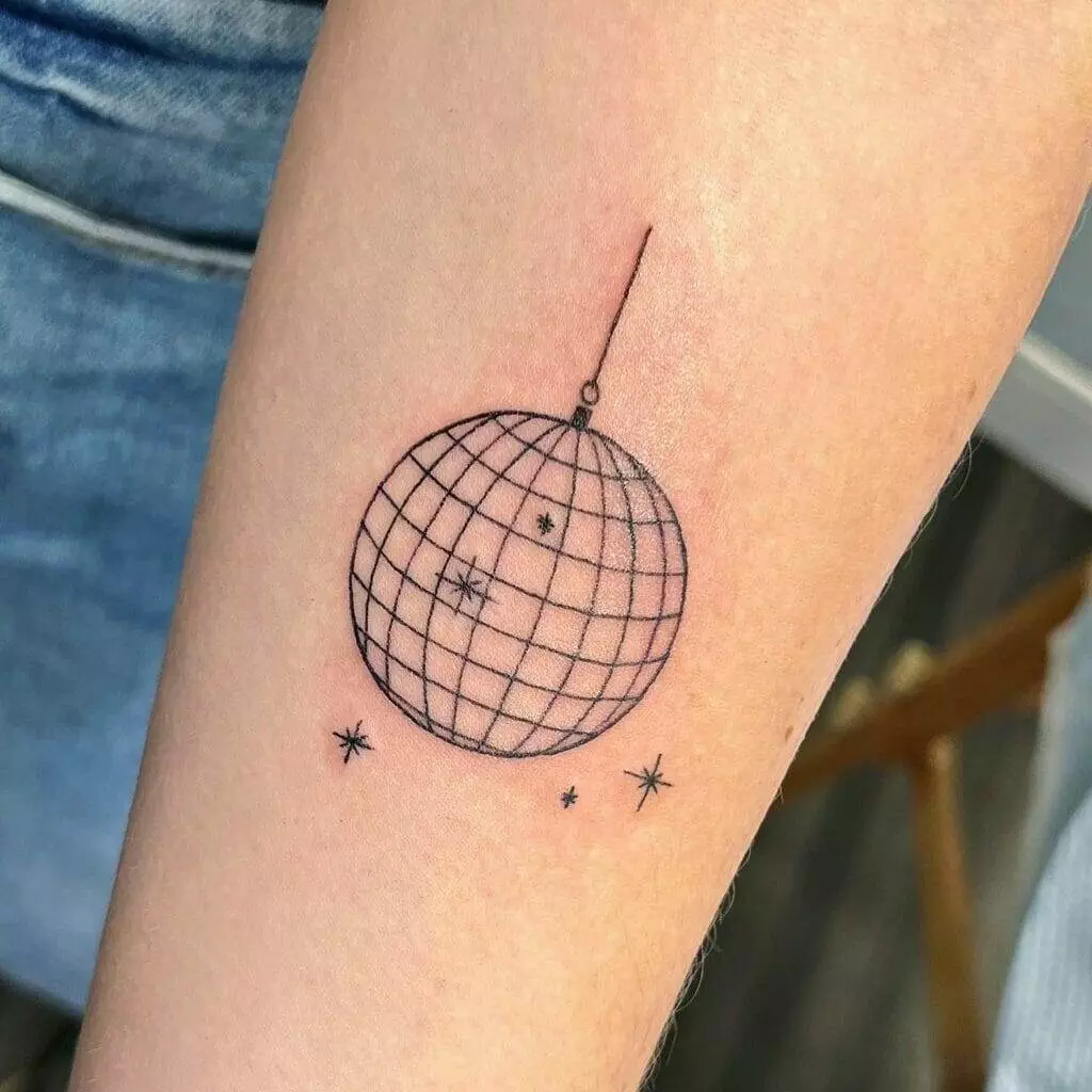 A small disco ball tattoo on the forearm.