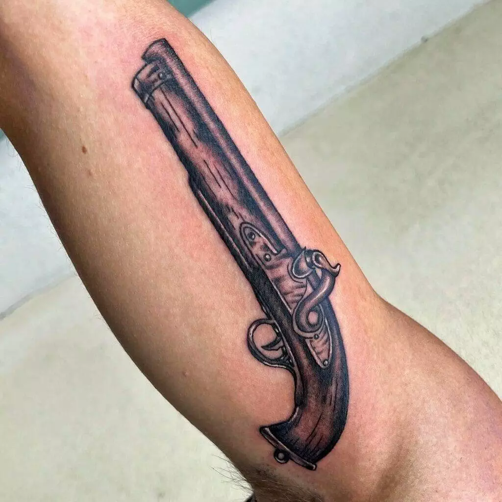 A tattoo of a gun on a man's arm.