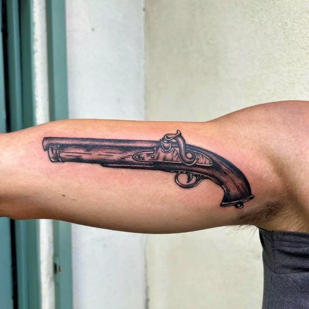 A man with a gun tattoo on his arm.