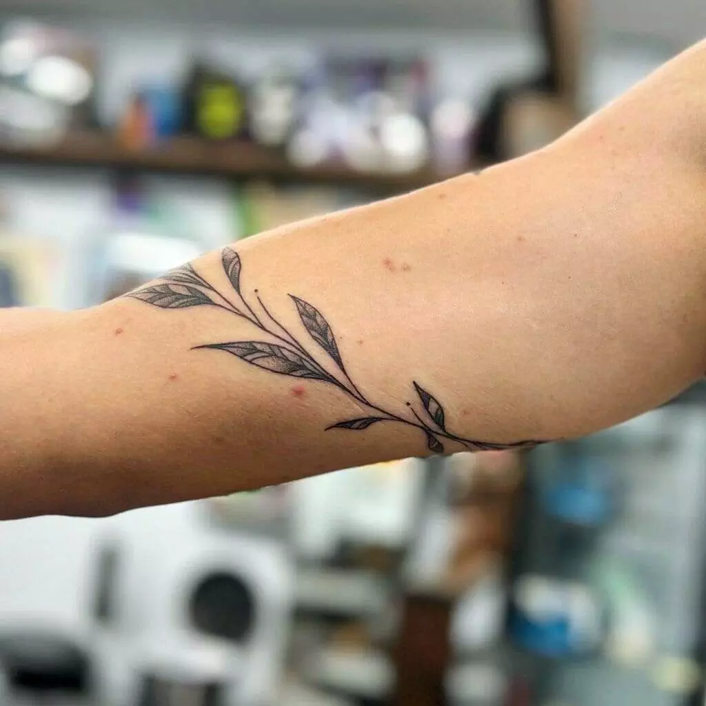 A woman with a tattoo of a leaf on her arm.