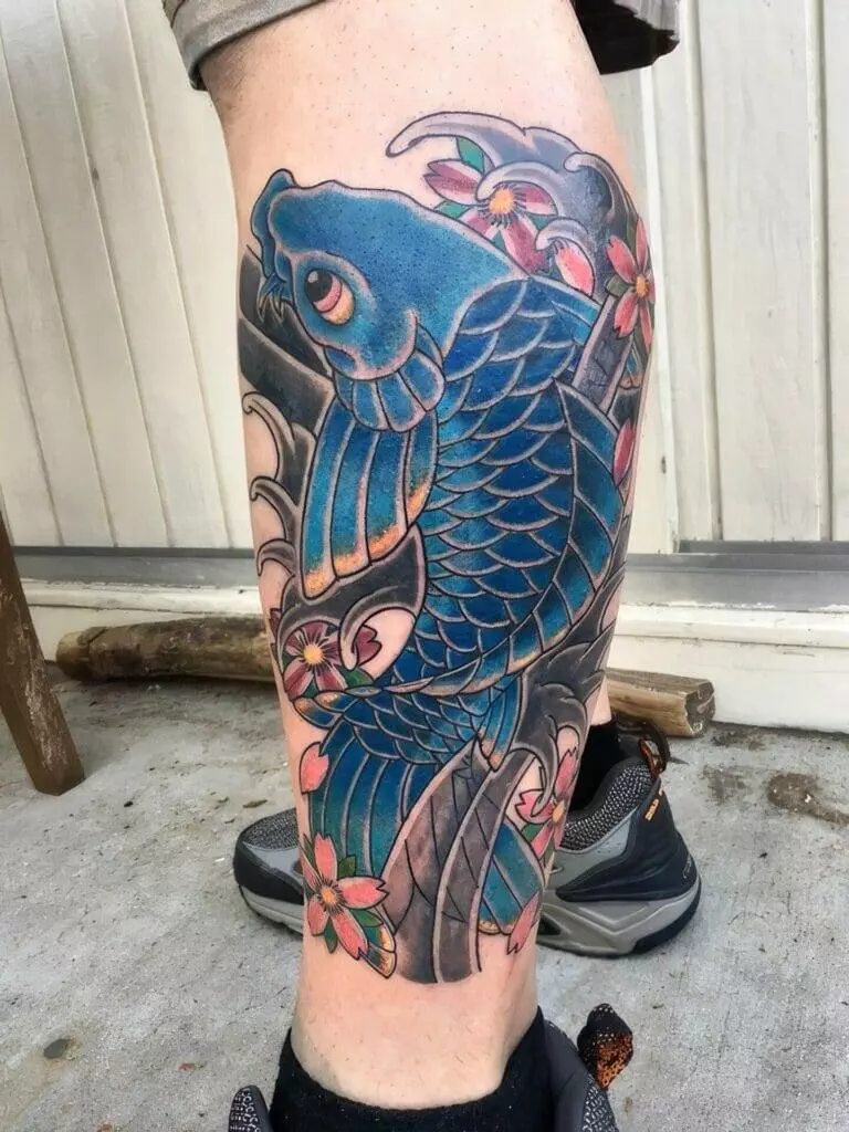 A blue koi fish tattoo on a man's leg.