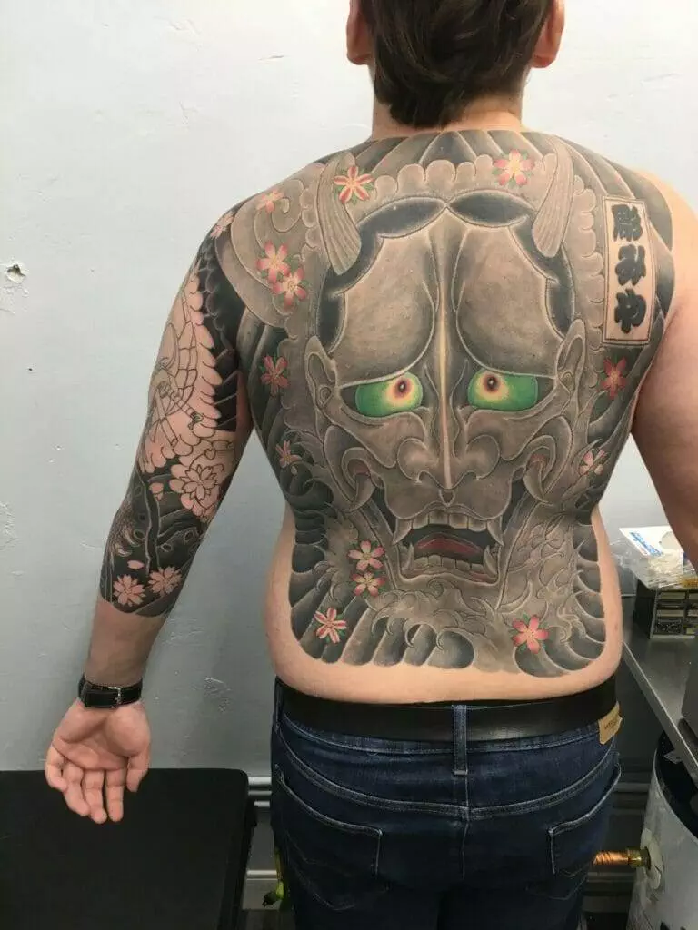 A man with a tattoo of a demon on his back.