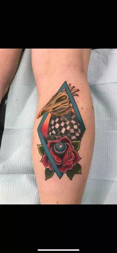 A woman's leg with a tattoo of a rose and a chess board.