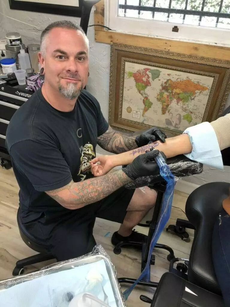 A man getting a tattoo on his arm.