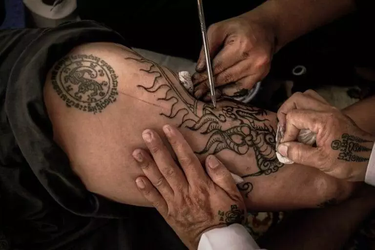 A man is getting a tattoo on his leg.