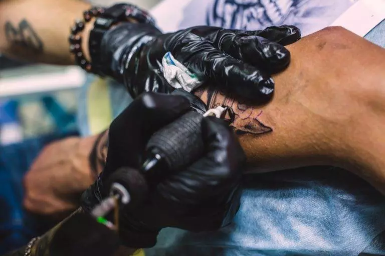 A tattoo artist is creating stunning cover-up tattoos to replace unwanted ink on a man's arm.