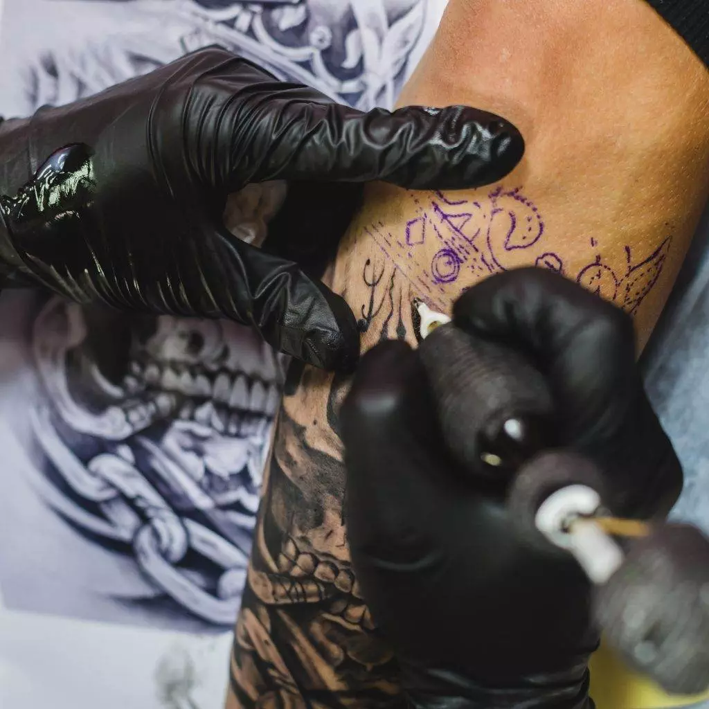 A tattoo artist is creating a stunning cover-up tattoo to replace unwanted ink on a man's arm.