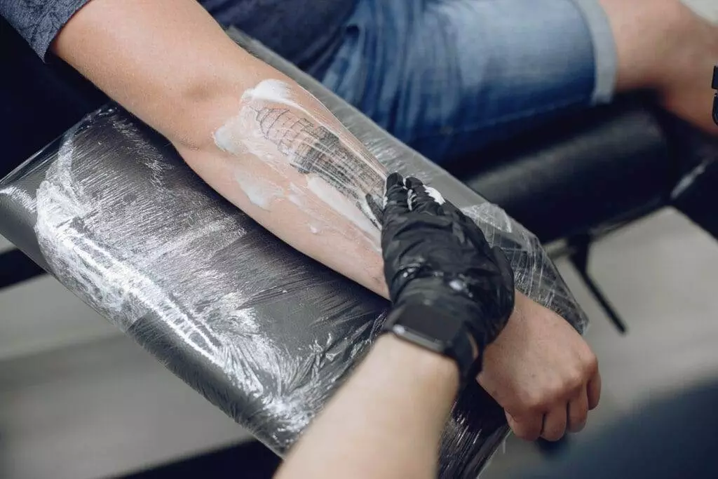 A man is getting a Neo-Traditional tattoo on his arm