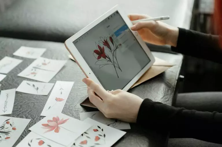 Person Holding White Ipad Displaying White and Red Flower