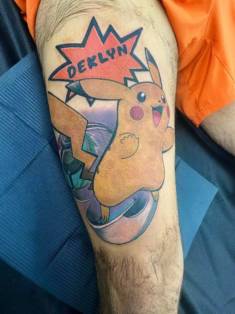 A colorful tattoo featuring Pikachu with a speech bubble containing the name 